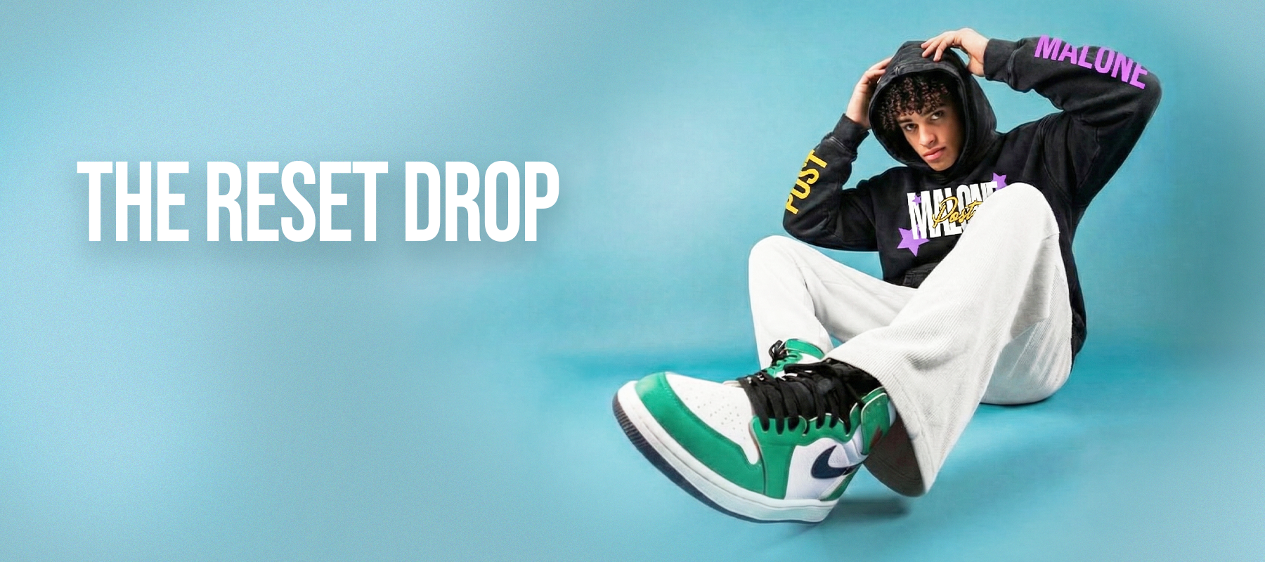 Streetwear model wearing oversized hoodie and sweatpants from Our Karma Clothing on blue studio background.